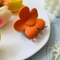 Detailed macro view of an orange flower hair claw clip on a stylish white ceramic tray - Orange & Grey