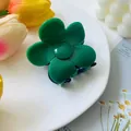 Detailed view of a bright green flower-shaped hair claw clip on a white ceramic tray - Green and Blue