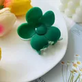 Close-up of green flower hair claw clip made of glossy resin on a white plate - Green and Light Green