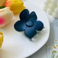 Detailed view of a dark blue flower hair claw clip with a glossy finish on white plate - Light Green and Blue Patchwork