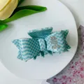 Blue and white checkerboard bow hair claw clip with rhinestone S detail on a white plate - Blue Plaid