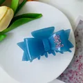 Blue bow hair claw clip with pink rhinestones and gold glitter finish on a plate - Starry Jelly Blue