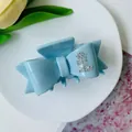 Light blue acetate bow hair claw clip with rhinestones shown on a decorative tray - Sky Blue