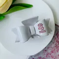 White acetate bow hair claw clip featuring a pink rhinestone letter B detail - White