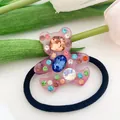 Macro detail of a pink resin bear hair tie with colorful crystal rhinestones and black band - Pink
