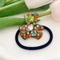 Close-up of a brown acetate bear hair tie with colorful crystal rhinestones on white flowers - 4-Amber