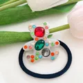 Dettaglio di un elastico per capelli a forma di orso con strass colorati e fascia elastica nera - Bianco
