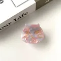 Detail of pink marble acetate cat hair claw clip with golden eyes on a book - Pink Floral