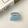 Détail d'une pince à cheveux en acétate bleu clair marbré sur un fond de table blanche - Moyen / Petit Monstre Bleu