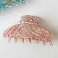 Macro detail of pink marble acetate hair claw clip with shimmering pearlescent finish - Pink