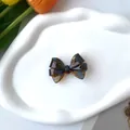 Detalle de pinza para el pelo con lazo de acetato de carey sobre una bandeja de nube - Pinza de Pico de Pato Caramelo