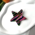 Macro di una molletta per capelli a stella con strisce di acetato su vassoio bianco - Multicolore a righe