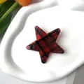 Detail of star-shaped red and black tartan hair clip on a white decorative ceramic tray - Red Plaid