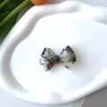 Detalle de pinza de pelo de acetato con textura de mármol en bandeja cerámica - Clip de Pico de Pato Gris Iridiscente