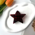 Star-shaped hair claw clip with red and black plaid pattern on a ceramic dish - Silver Star