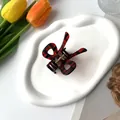 Close-up of a red and black plaid butterfly hair claw clip on a white decorative tray - Butterfly Claw