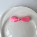 Minimalist bright pink bow hair clip with glossy acetate finish in a ceramic dish - Pink