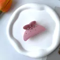 Detalle de una pinza para el pelo rosa con diamantes de imitación en bandeja blanca - Rosa
