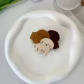 Detailaufnahme von drei bunten Hunde-Haarklammern auf einem dekorativen weißen Keramikteller - 6cm / Kaffee Hund