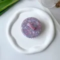 Detail view of purple marble acetate scalp massage comb on white decorative tray - Purple