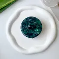 Top view of circular acetate scalp massager with green marble texture on a white tray - Dark Green