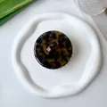 Top view of a round tortoiseshell resin hair claw clip on a white decorative ceramic plate - Dark Tortoiseshell