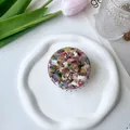 Overhead view of a colorful marble pattern acetate hair claw clip on a white ceramic tray - Floral