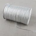 Close-up of sparkling silver metallic ribbon on a white spool for DIY gift packaging - Silver