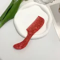 Macro shot of red marble pattern acetate hair comb with ergonomic handle on ceramic tray - Red Floral