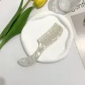 Detailed view of wide-tooth acetate hair comb with marble pattern in a lifestyle setting - White