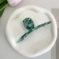 Detailed macro of dark green marble acetate hair claw clip on a ceramic tray display - Green Marble