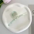 Close-up of mint green marble acetate hair claw clip on minimalist ceramic tray - Light Green Texture