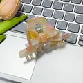 Elegante pinza per capelli con fiocco marmorizzato rosa e giallo su sfondo laptop - Arancione