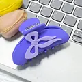 Matte purple claw clip with lavender bow detail shown on a grey keyboard background - Purple