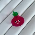 Close-up of a mini carrot-shaped hair clip with a cute smile face design - Beetroot Shape