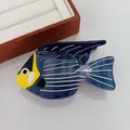 Pince à cheveux en forme de poisson bleu en acétate avec détails jaunes sur support blanc - Poisson Bleu