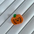 Macro view of a mini pumpkin acetate hair claw clip with a cute smiling face design - Pumpkin Shape