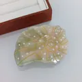 Détail d'une pince à cheveux coquillage avec spirales dorées et texture en acétate - Conque Verte