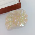 Détail macro d'une pince à cheveux en forme de conque en acétate avec finition irisée perle - Conque Nacrée