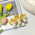 Three mushroom acetate hair claws in yellow and white displayed on a laptop - Yellow