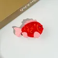 Détail d'une pince à cheveux créative en acétate rouge en forme de baleine avec accents roses - Poissons Embrasseurs