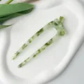 Detail view of large green marble acetate U-shaped hair pin with elegant bow design - Green