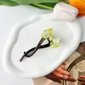 Detailaufnahme einer grünen Haarklammer mit Schleife auf einem dekorativen Keramikteller - Gelb