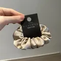 Detalle de un coletero de satén oro champán en una tarjeta de exhibición negra - Albaricoque