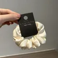 Detail showing high-quality cream silk satin scrunchie with Korean brand tag - Off-white