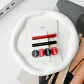 Detail view of three minimalist red and black acetate hair clips on a white display card - Red + Black