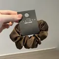 Primer plano de un coletero de satén marrón con etiqueta de marca nyu.nyu estilo coreano - Café Oscuro