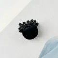 Detail of a glossy black antler-shaped hair claw clip on a stylish textured background - Black