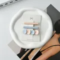 Detailed view of pastel resin hair clips in pink and blue on a white ceramic tray - Light Pink and Blue