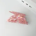 Detailed view of iridescent pink butterfly hair claw clip with a hollow design - Pink
